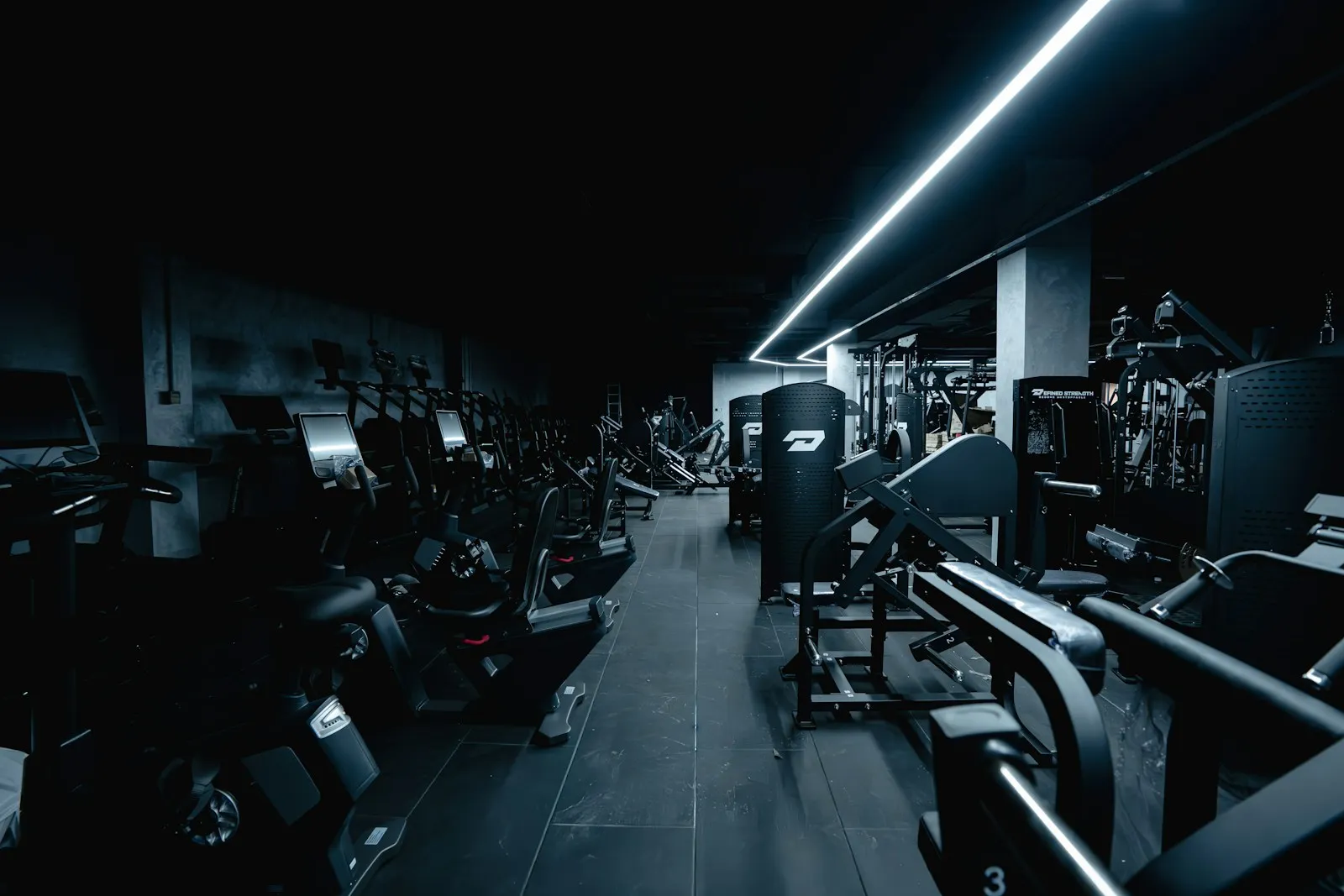 A dark gym interior with rows of training equipment.